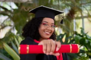 Femme souriante portant une robe académique et un chapeau académique noir