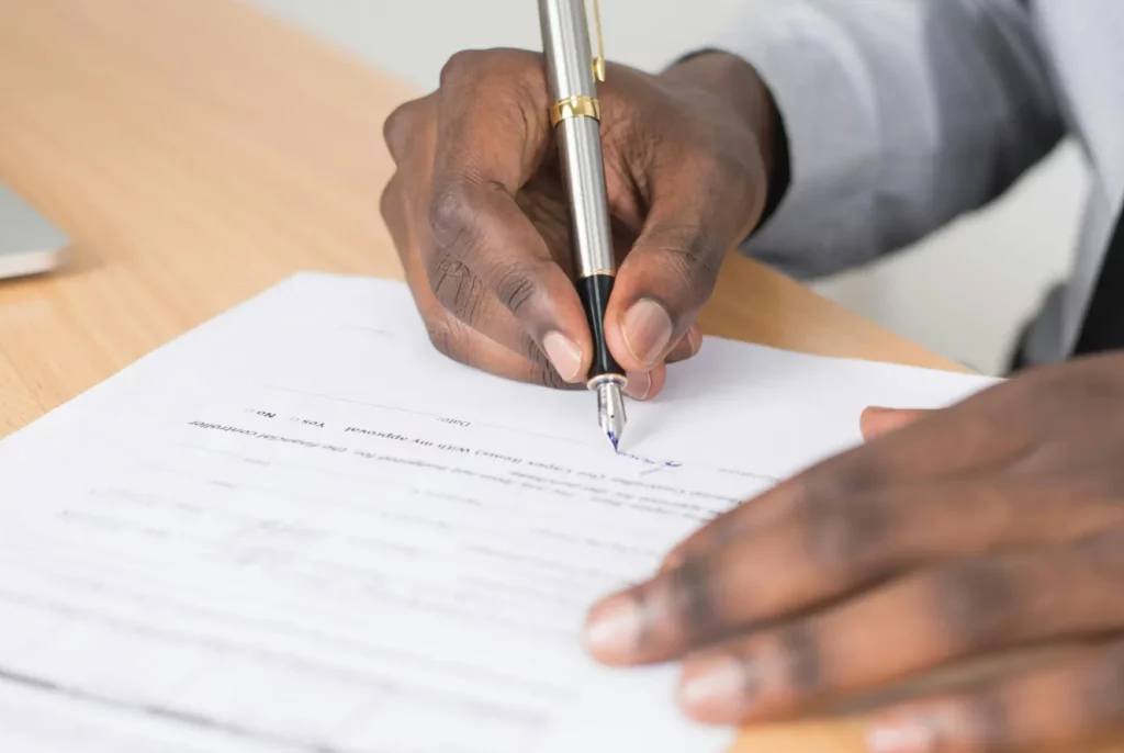 Personne Tenant Un Stylo Torsadé Gris Et Papier D'imprimante Blanc Sur Une Table En Bois Brun